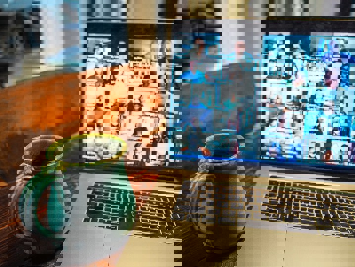 A close up image of a laptop showing a Zoom conference call and a mug next to the laptop.