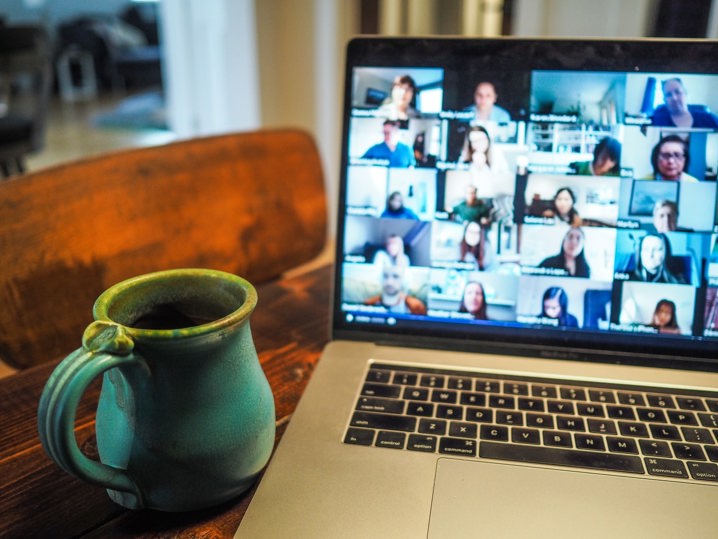 A close up image of a laptop showing a Zoom conference call and a mug next to the laptop.