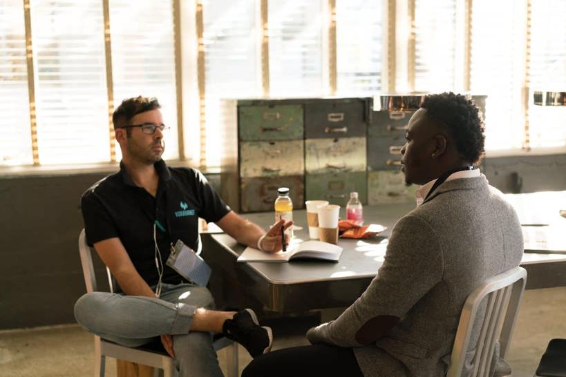 Two men sitting at a table having a formal work conversation.